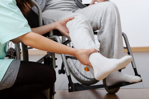 patient en fauteuil roulant en train de se faire examiner le pied par un docteur