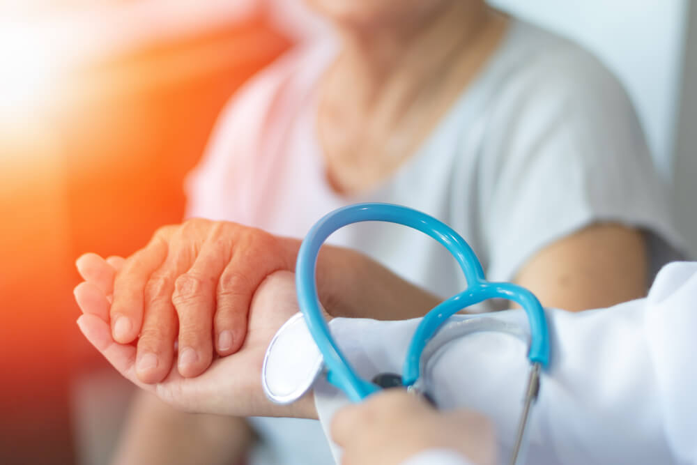 Médecin avec stéthoscope prenant la main d'une patiente