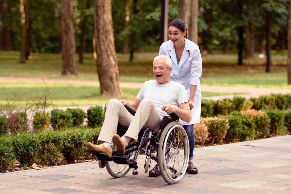 Infirmière plaisantant avec un patient en fauteuil roulant à l'extérieur